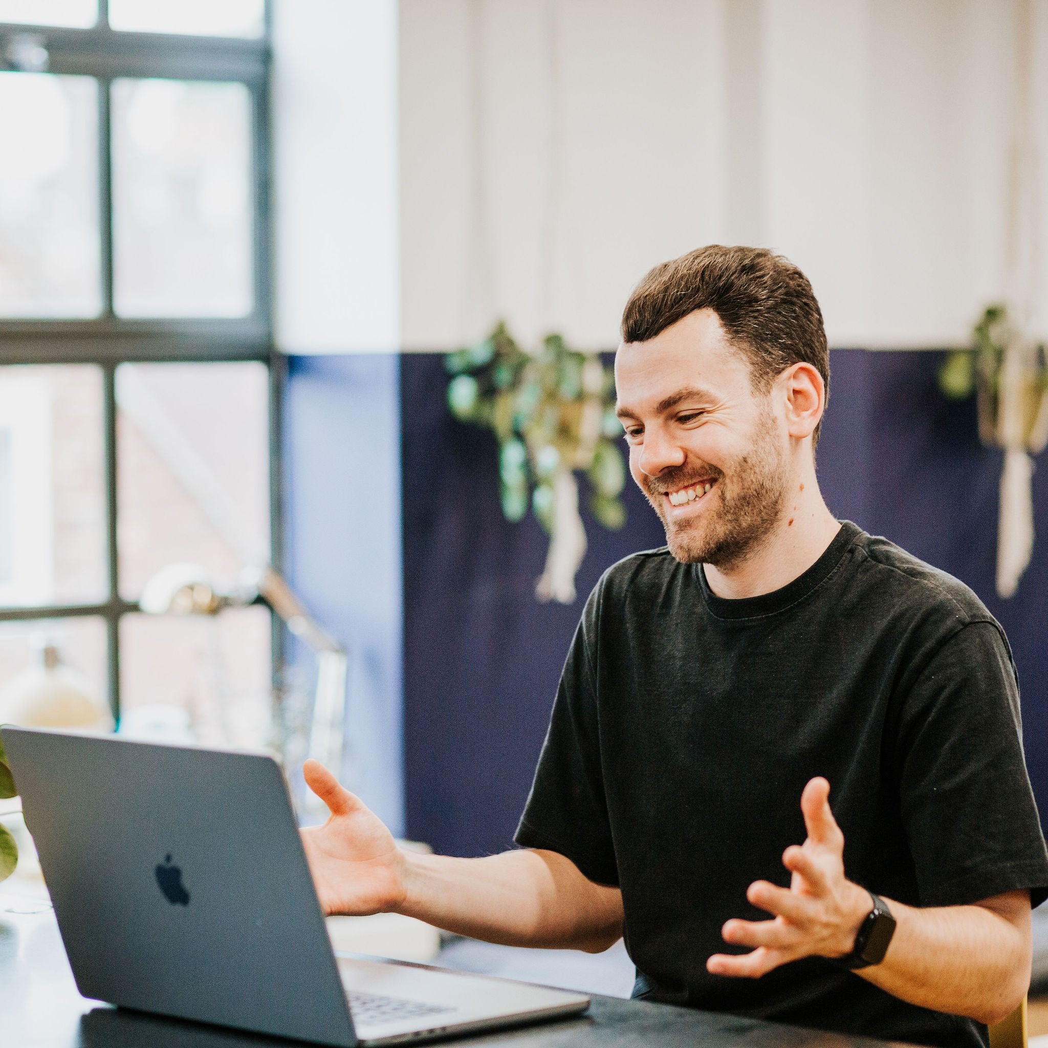 Man in a black t-shirt using a laptop in a modern office setting