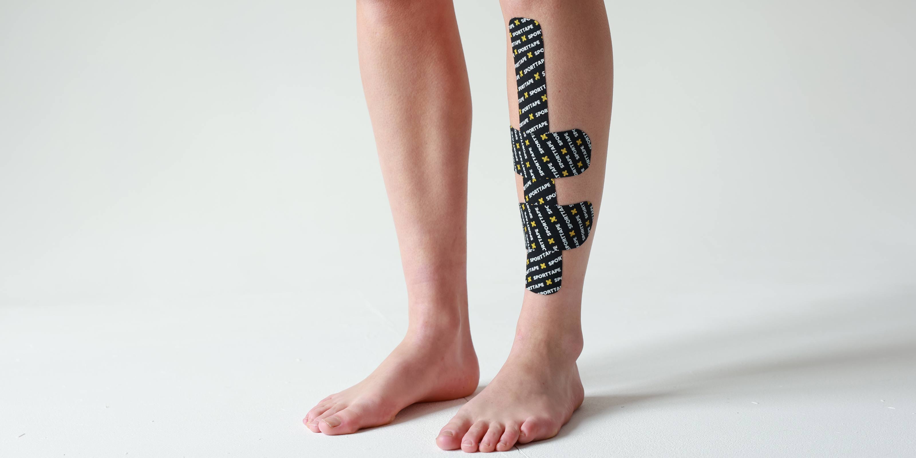 Person wearing SPORTTAPE branded kinesiology tape on the shin