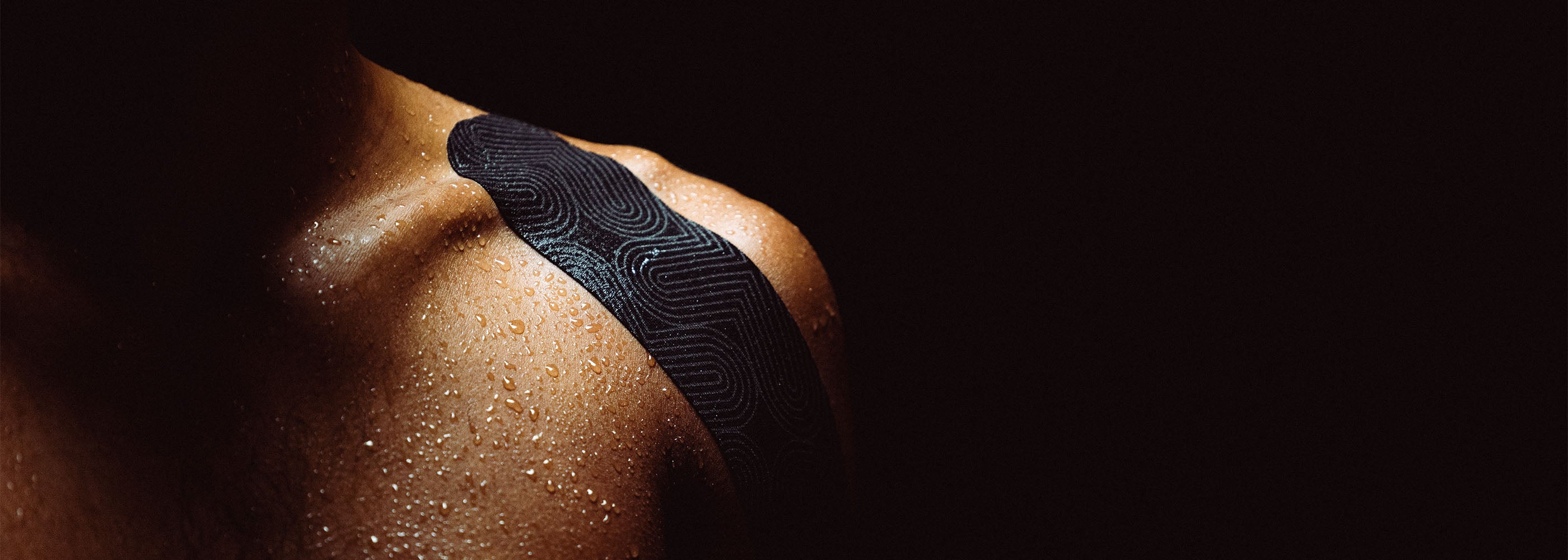 Platinum Kinesiology on a person's shoulder against a dark background