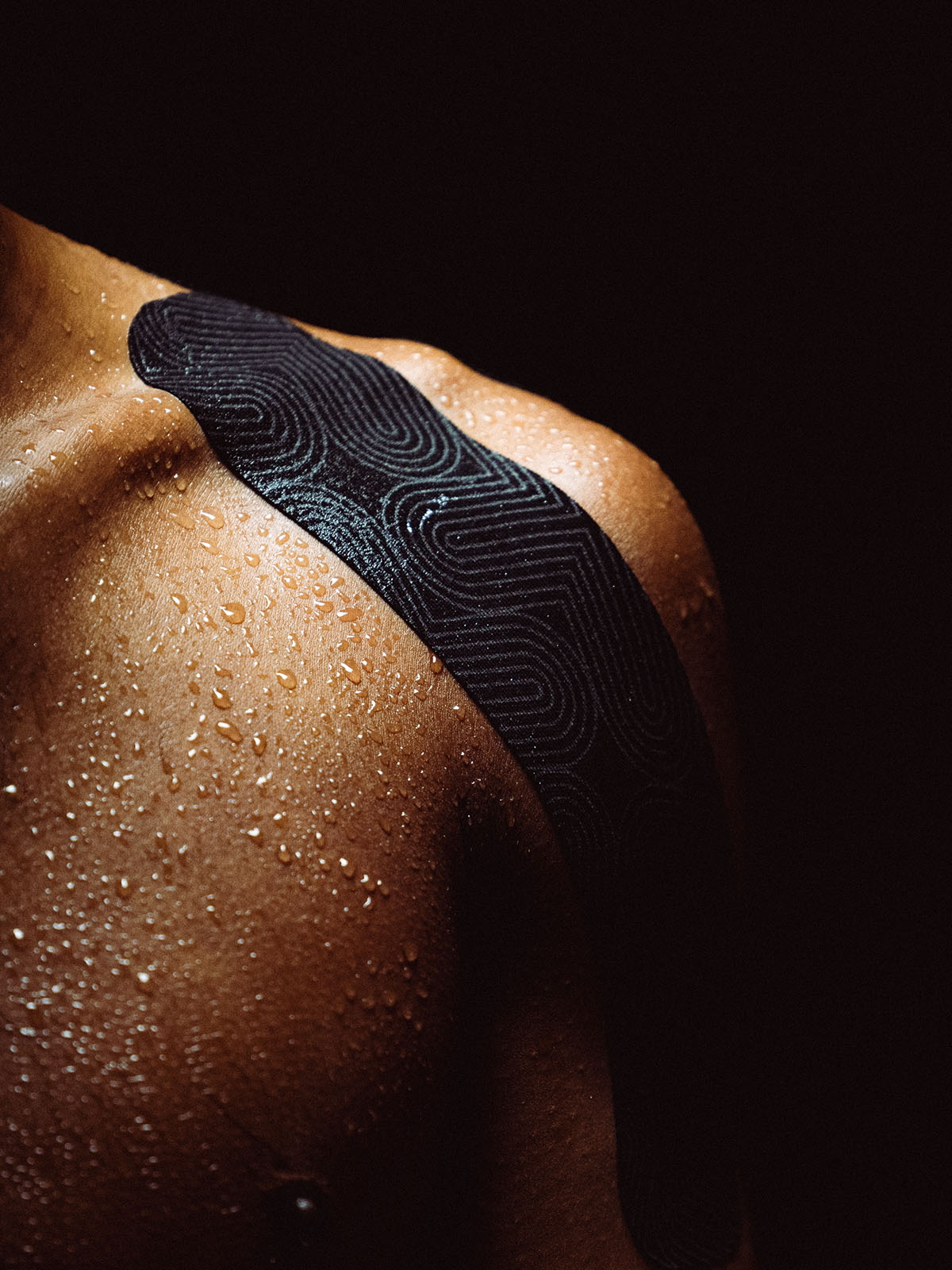 Platinum Kinesiology on a person's shoulder against a dark background