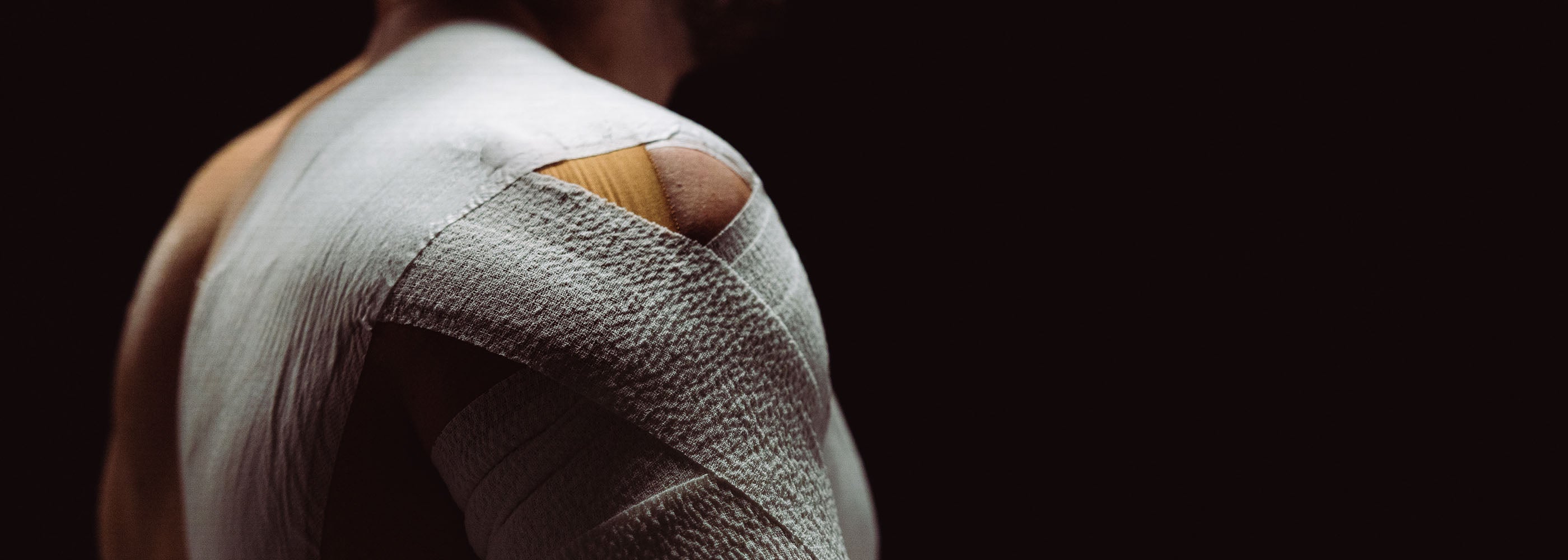 Person with a bandaged arm and shoulder on a black background