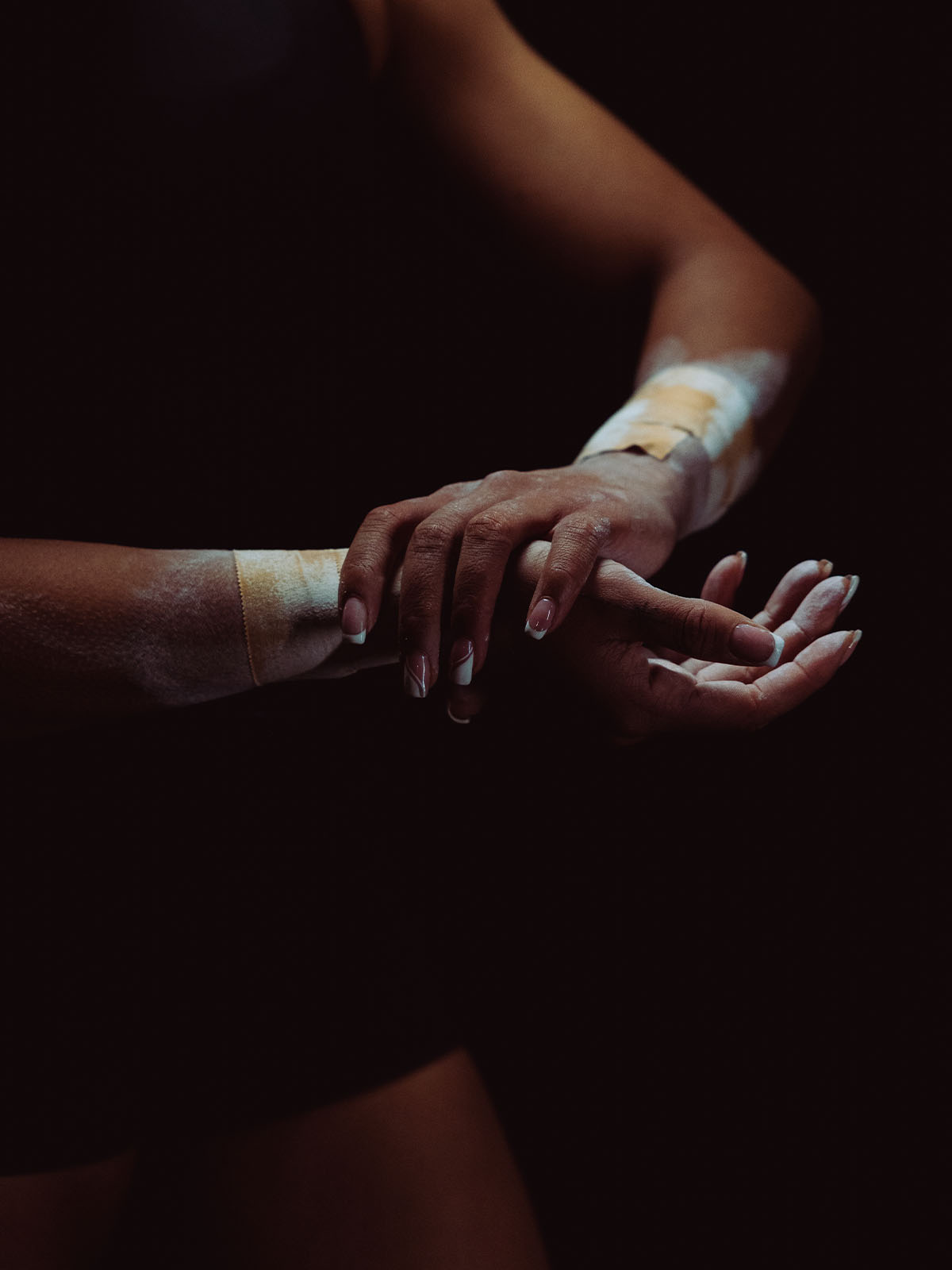 Athlete applying chalk to hands with zinc oxide tan tape on both wrists