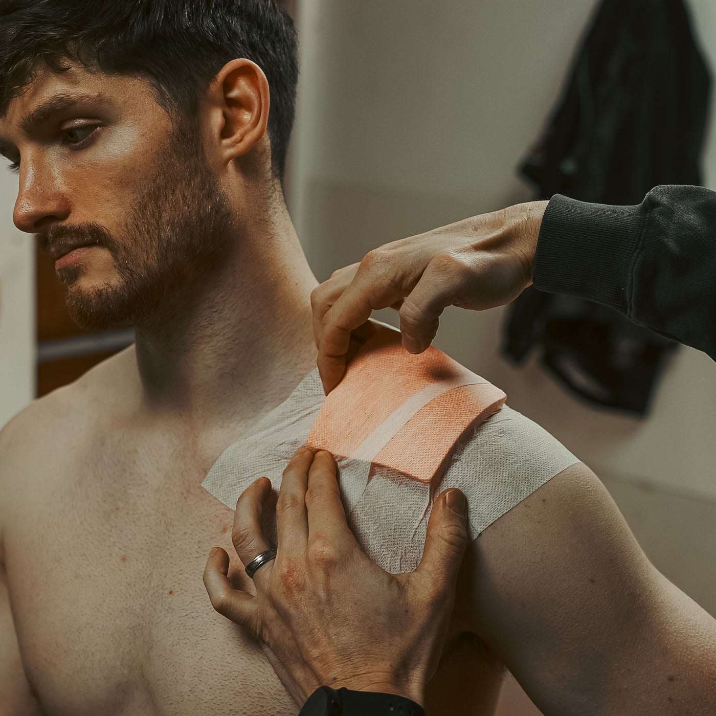 Man having a dermal pad and fixation tape applied to his shoulder