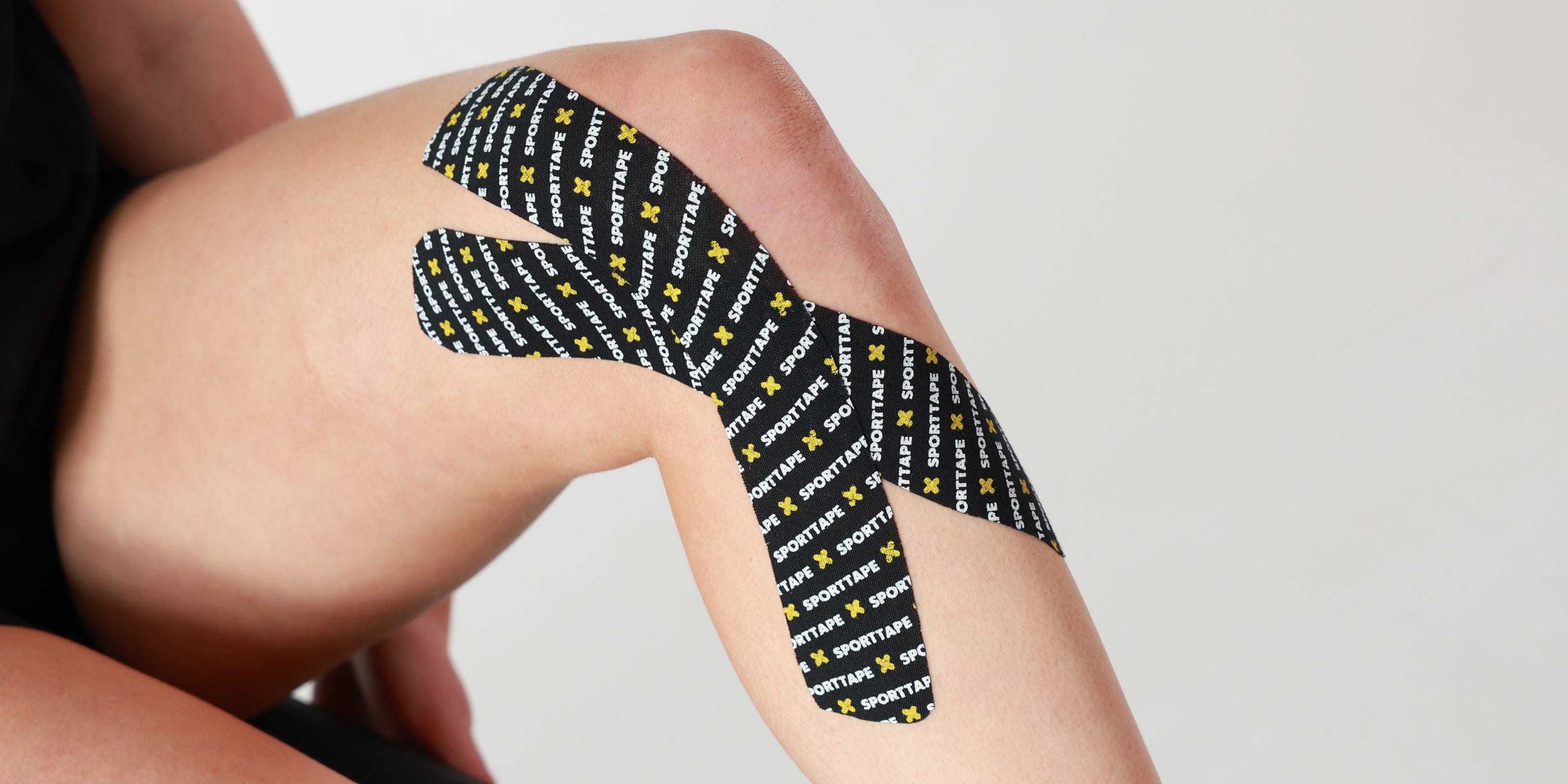 Person wearing SPORTTAPE branded kinesiology tape on the inner knee
