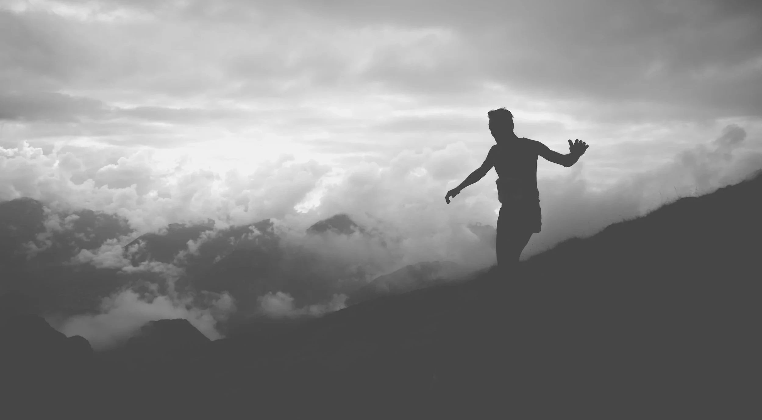 Silhouette of a person standing on a mountain with a dramatic sky