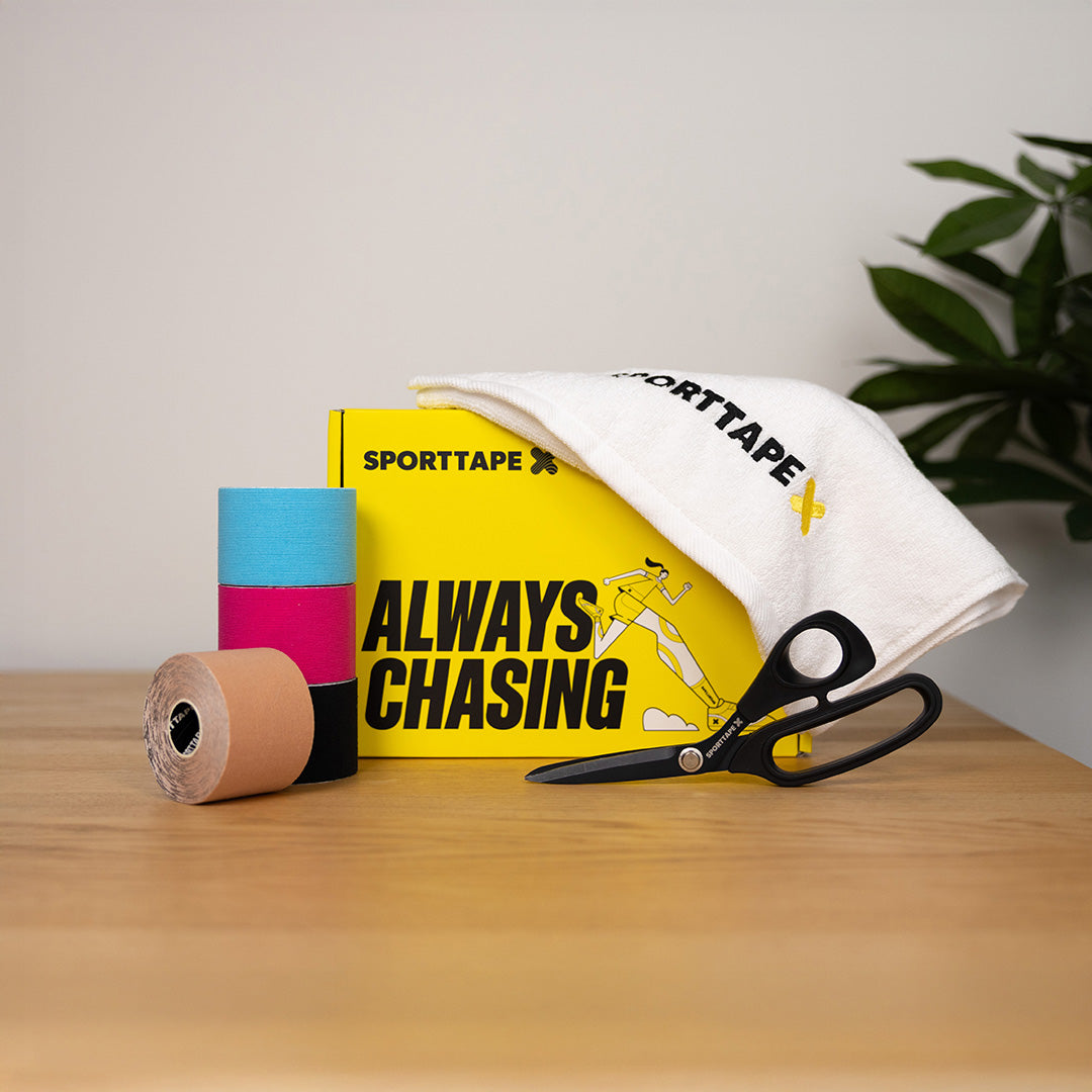 Sporttape with scissors and a branded towel on a wooden surface