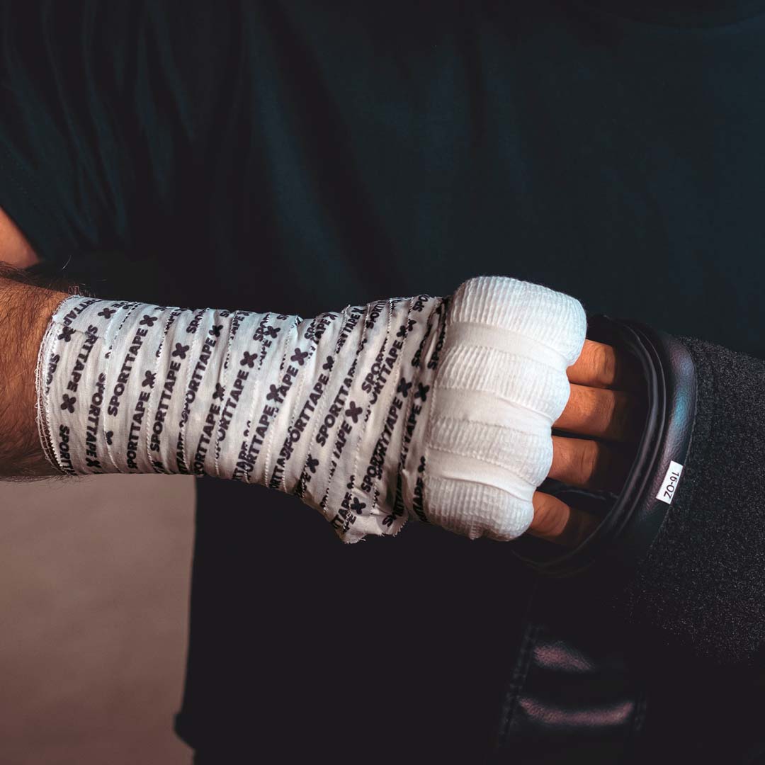 Picture of boxing hand wrap and athlete putting their hand into a boxing glove.